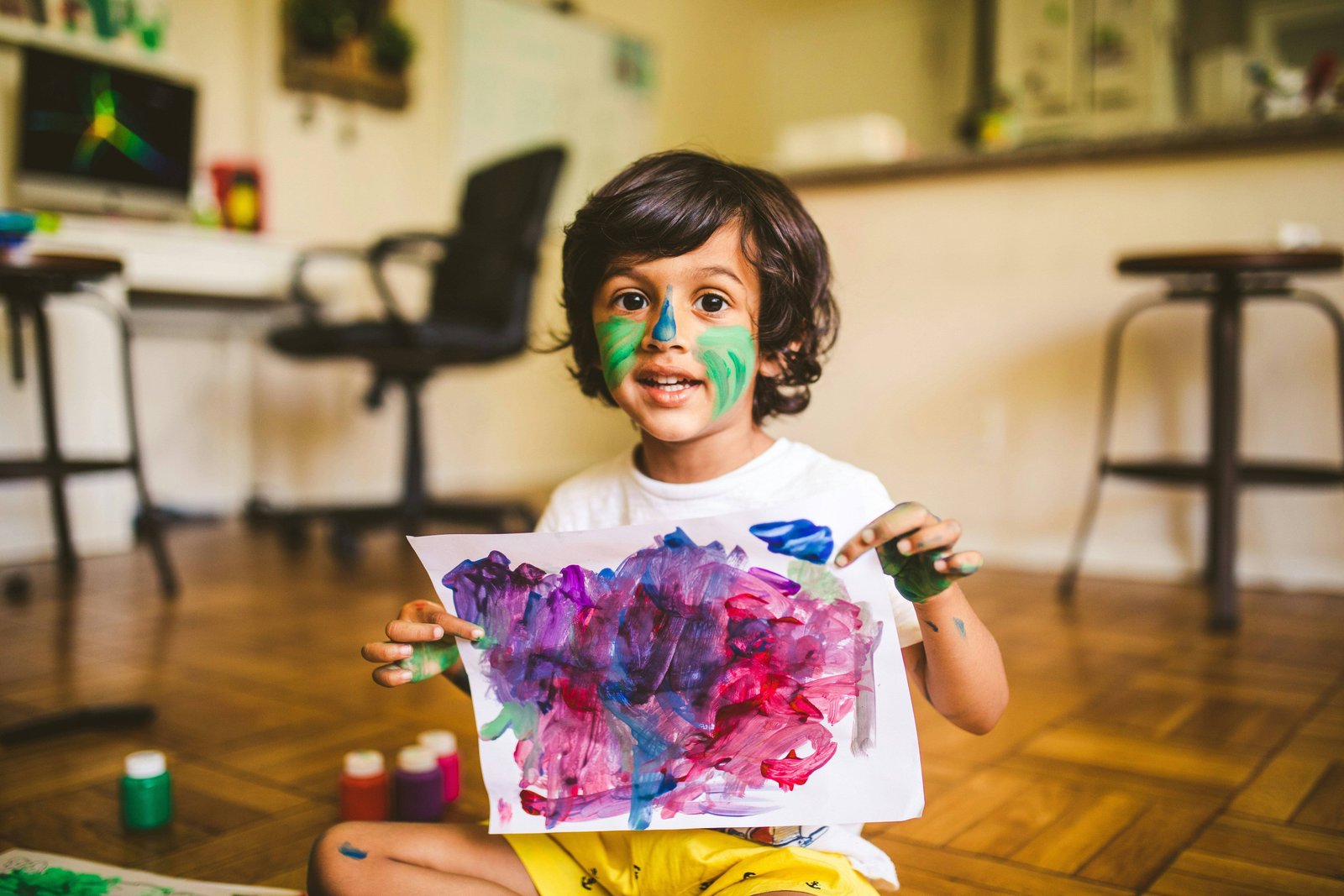 Smiling child holding a colourful finger painting