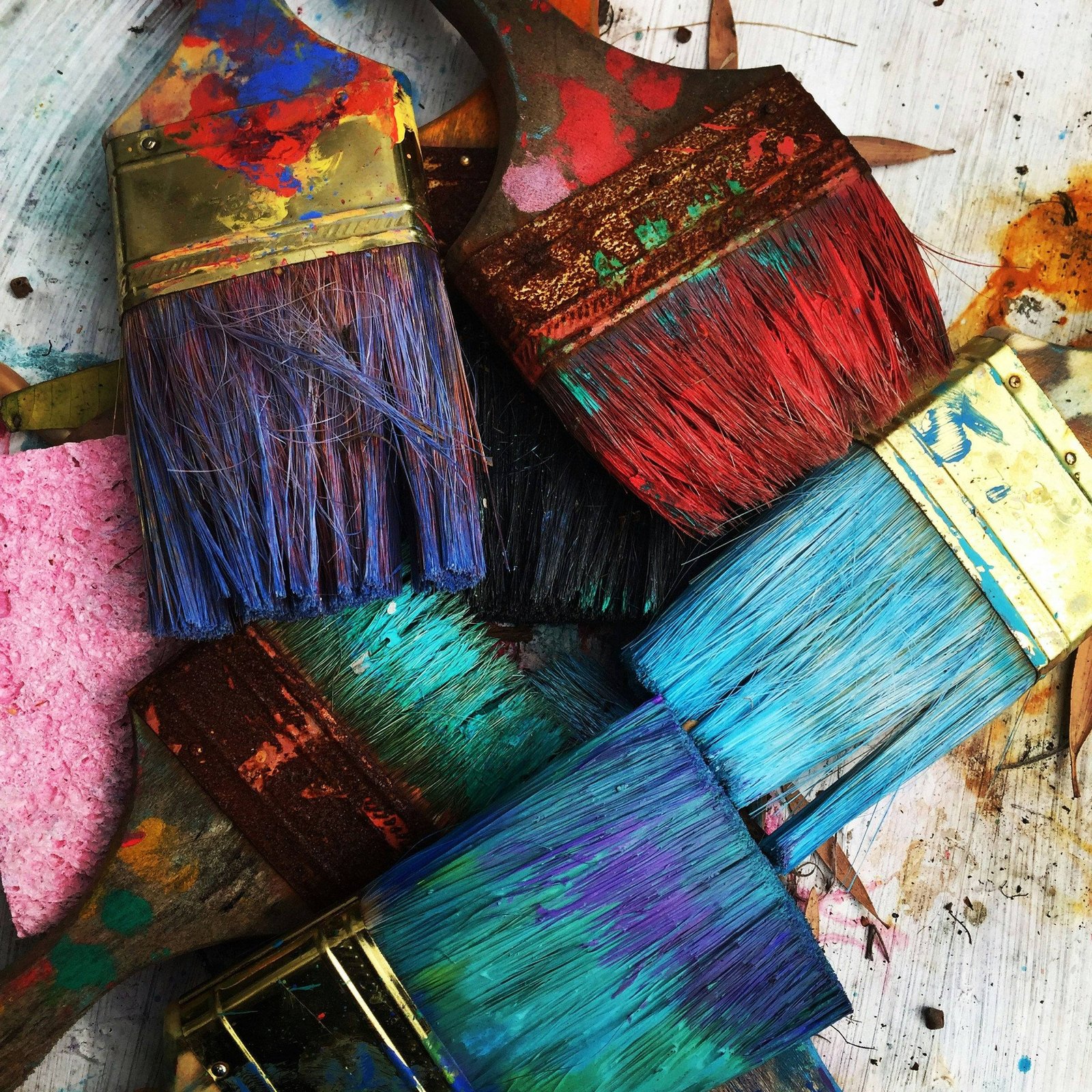 Pile of colourful paint-covered brushes