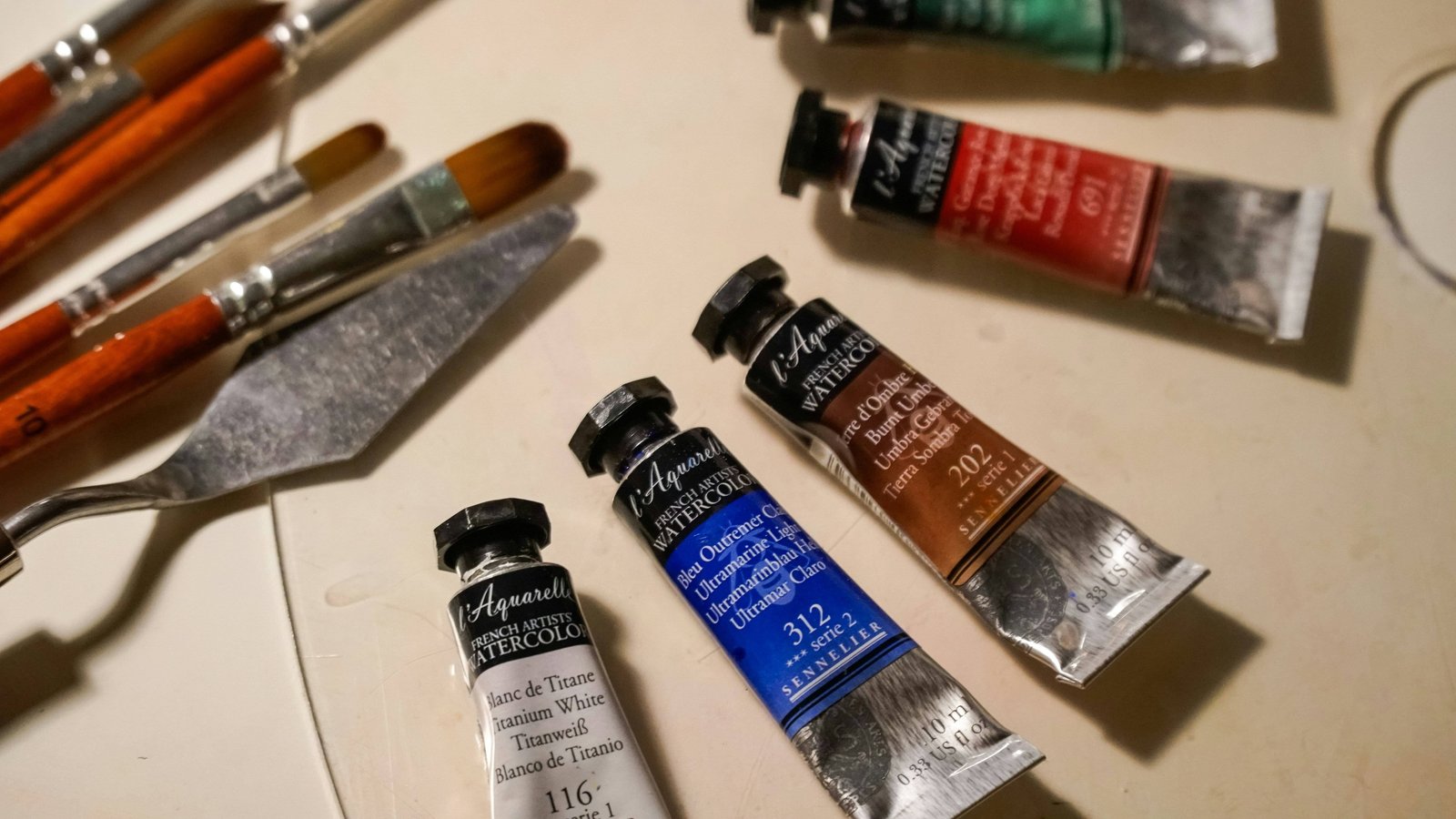 Tubes of watercolour paint beside brushes