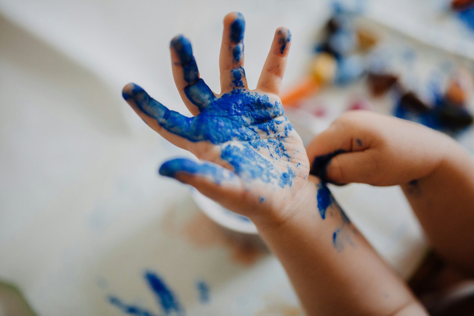 Smiling child holding up a colourful finger painting